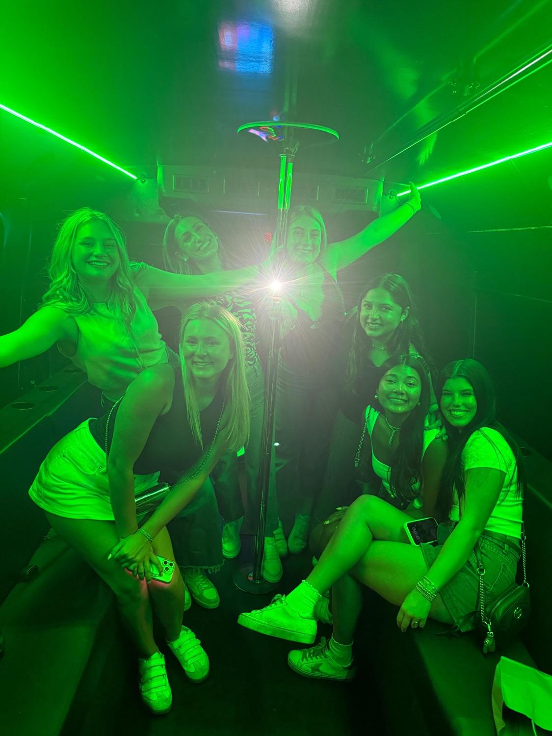Friends celebrating on AUX bus under green lighting