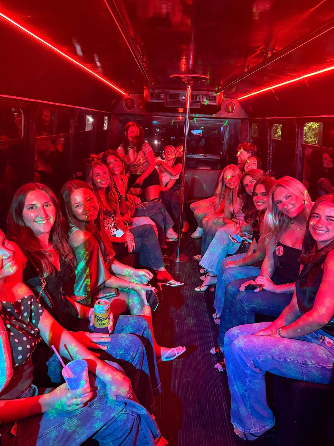 Group of riders on an AUX party bus under red neon